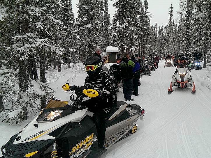 A group of people riding their snowmobiles.