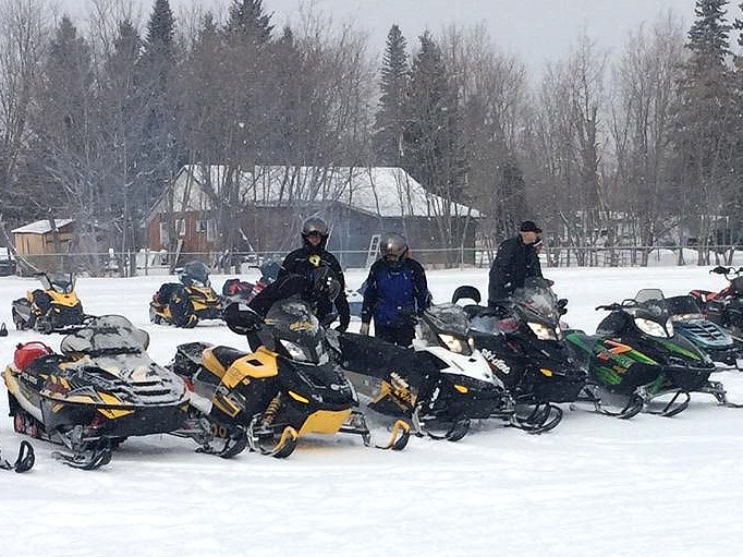 A group of people preparing to ride their snowmobiles.